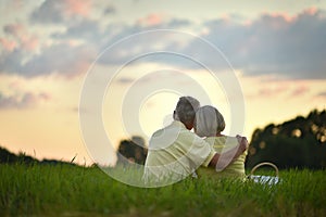 Back view. Happy elderly couple resting at sunset