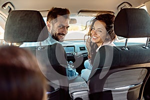 Back view of happy family riding car, mother and father turning back to daughter, enjoying road trip on vacation