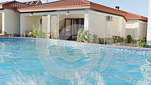 Back view happy girl running and jumping in swimming pool, children having fun, splashing water. Summer travel family