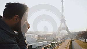 Back view happy male Caucasian journalist taking a picture of Eiffel Tower in Paris with vintage film camera slow motion