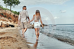 Back view of happy middle aged couple walking on a deserted beach