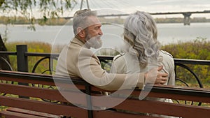 Back view happy senior mature 60s husband wife hugging on bench outdoors healthy retirement couple mid aged woman man