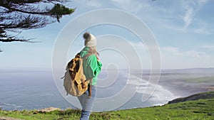 Back view of happy tourist woman with back pack walking scenic Point Reys beach