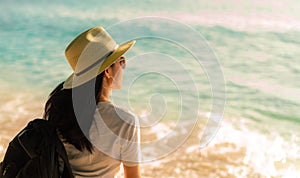 Back view of happy young Asian woman in casual style fashion with straw hat and backpack. Relax and enjoy holiday at tropical