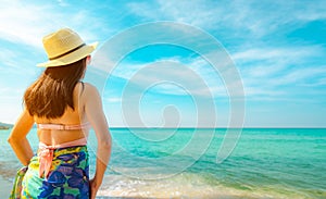 Back view of happy young Asian woman with straw hat relax and enjoy holiday at tropical paradise beach. Girl in summer vacation