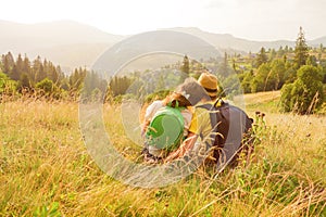 Back view. Happy young couple sitting on mountain couple looking at view mountain love couple nature vacation green