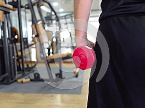 Back view of healthy young man holding dumbbell at sport gym. Fitness and workout concept