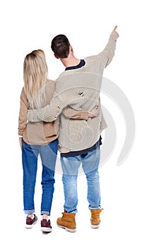 Back view of a heterosexual couple who hugs and points out.