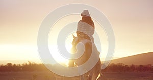 Back view, horse riding or woman in farm at sunset with rider or jockey for adventure, peace or wellness. Relax, ranch