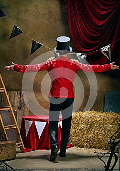 Back view. Illusionist or showman. Young man retro circus entertainer announces start of show isolated over dark retro