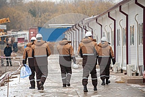 Back view of industrial construction workers wearing uniform on a cold weather