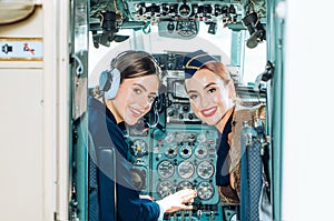 Back view from the inside of the plane. Portrait of two attractive young women pilots with headset preparing to fly