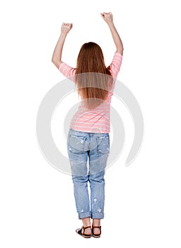 Back view of joyful woman celebrating victory hands up.