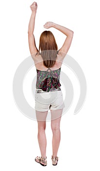 Back view of joyful woman celebrating victory hands up.