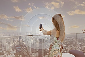 Back view  lifestyle tourist woman take a picture by Photo camera of a smartphone with evening  scene in the cityscape on the