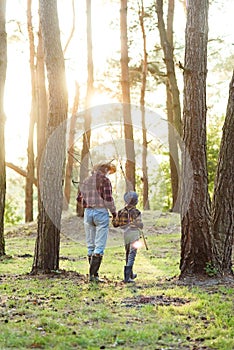 Back view likable bearded grandpa in forest going fishing together with his 10-aged grandson and talking about fishing.