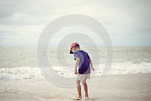 Back view of little boy walking along the beach during the sunset