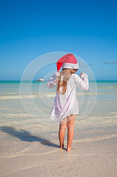 Back view of Little cute girl in red hat santa