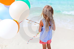 Back view of little girl with balloons at beach