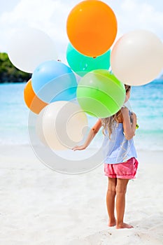 Back view of little girl with balloons at beach