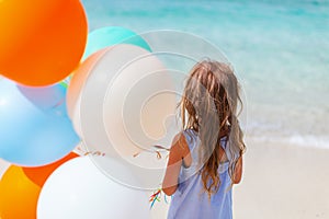 Back view of little girl with balloons at beach