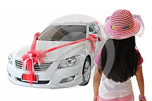 Back view of little girl looking at new car with red bow as pres