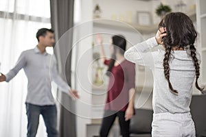 In back view, Little girl puts her hands on her ears because she does not want to hear her dad and mom quarrel. close ears, Family