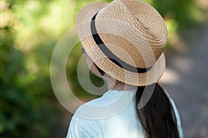 Back view of a little girl wearing a straw hat in the park