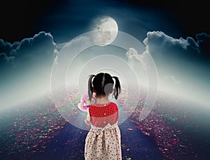 Back view of lonely child with doll sad gesture on pathway with