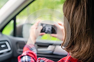 Back view of lonely girl with mobile phone near rainy window with drop of car.