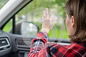 Back view of lonely girl touching by hand rainy window with drop of car.