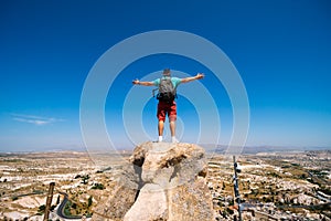 Back view. Man with arms spread apart enjoy the life. Uchisar Castle. Tourist at the top of the fortress, mountains, view of