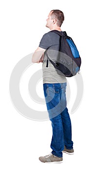 Back view of man with backpack looking up.