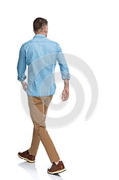 Back view of man with blue jeans shirt and chino pants walking photo