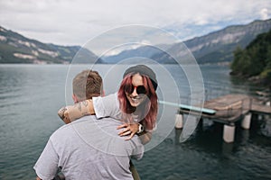 back view of man carrying happy young woman in sunglasses near majestic mountain lake
