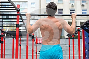 Back view of man doing pull up at the gym. concept of sport. exercises in fitness gym. Male shirtless model doing