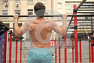 back view of man doing pull up at the gym. concept of sport. exercises in fitness gym. Male shirtless model doing