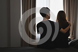 Back view of man embracing his wife and sitting in bed room. Comforting, encouraging and understanding.