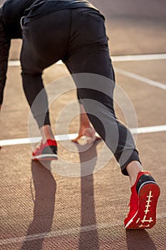 Man feet in starting position for running on race track in stadium