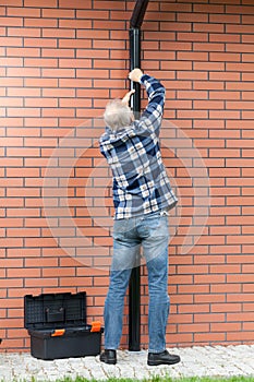 Back view of a man fixing gutters