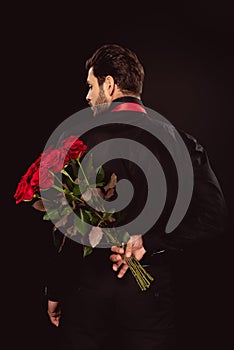 Back view of man in formal wear holding bouquet of roses