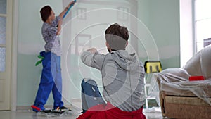 Back view man gesturing talking to blurred woman painting wall in new home. Joyful Caucasian young husband chatting with