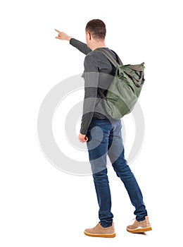 Back view of a man with a green backpack pointing forward.