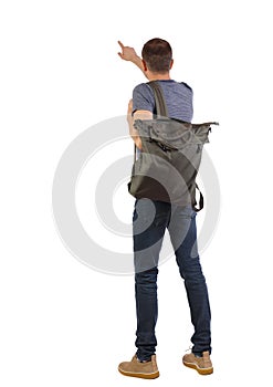 Back view of a man with a green backpack pointing forward