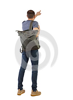 Back view of a man with a green backpack pointing forward