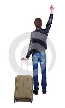 Back view of man with green suitcase greeting waving