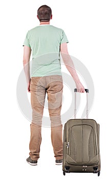 Back view of man with green suitcase looking up