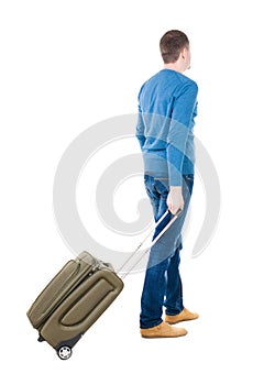 Back view of man with green suitcase looking up.
