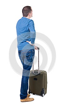 Back view of man with green suitcase looking up.