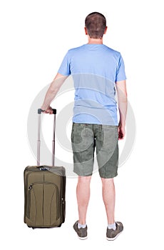 Back view of man with green suitcase looking up.